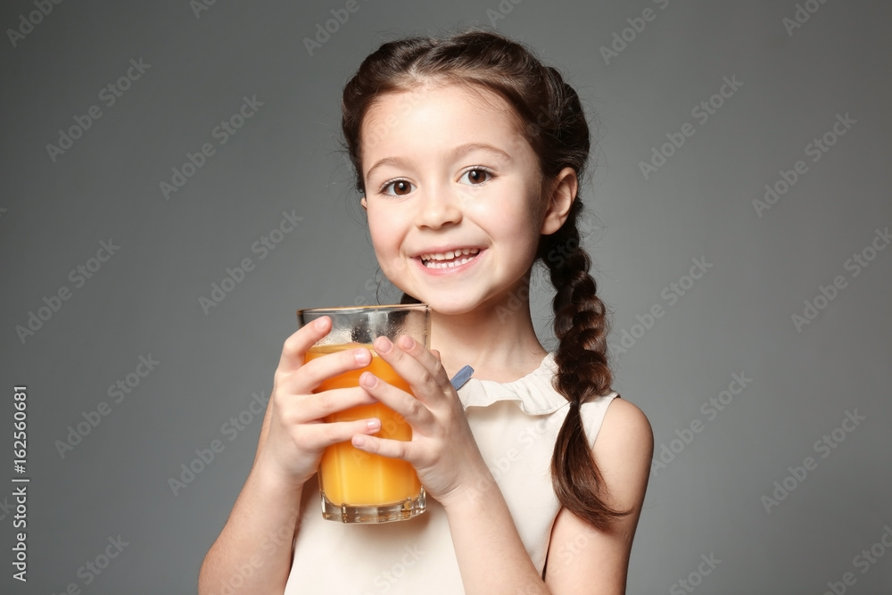 Cute little girl with glass of juice on grey background Cute little girl with glass of juice on grey background