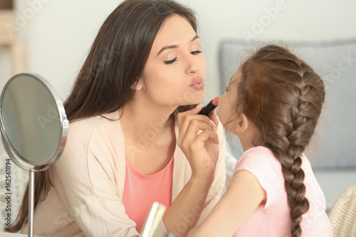 Young woman making up her daughter at home