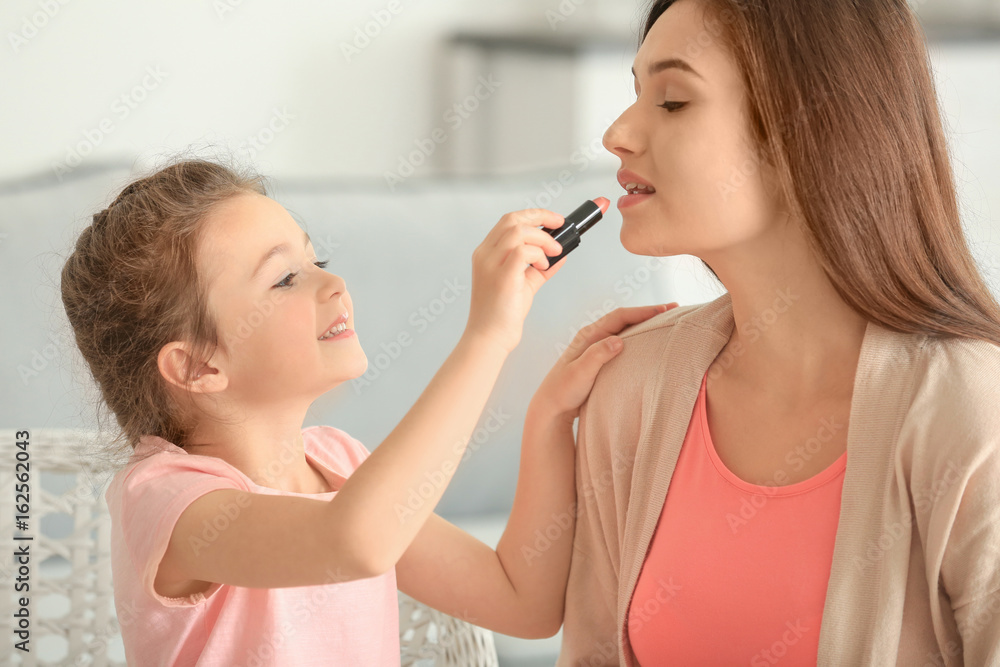 Little girl making up her mother at home