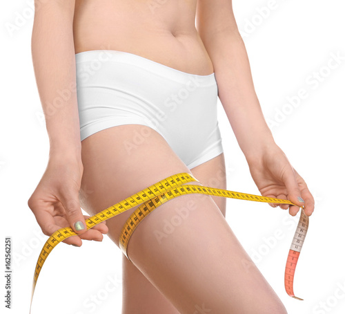 Beautiful young woman in underwear with measuring tape on white background, closeup. Diet concept