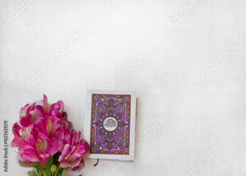Holy Quran with flowers on white wooden background