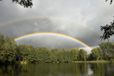 Wolkenverhangener See mit Regenbogen, cloudy lake with strong rainbow