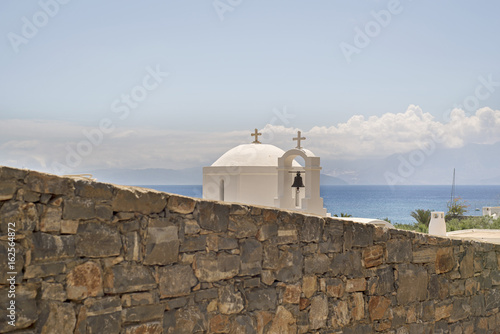 Greek orthodox church behind the stone wall near the beach