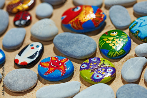 Rounded colorful stones pebbles shingle with pictures painted on them