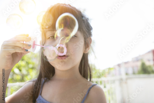 Cute little girl is blowing a soap bubbles  outdoor shoot 