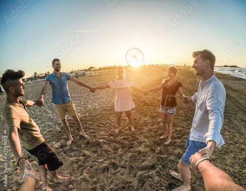 Tableau sur toile Firsthand view of happy friends having fun on the beach party at sunset - Young