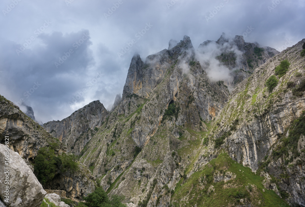 Beautiful landscape of the mountains in Picos de Europa in Spain; hiking trail in foggy and cloudy summer day