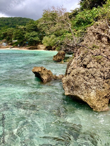 Secret romantic cove: Sand beach, tropical lush greenery, rock stones & crystal clear blue water wave ocean in the Portland Parish of the Caribbean island of Jamaica photo