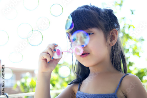 Cute little girl is blowing a soap bubbles  outdoor shoot 