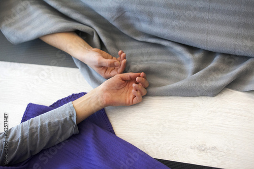 Closeup of the hands of two woman lying in savasana