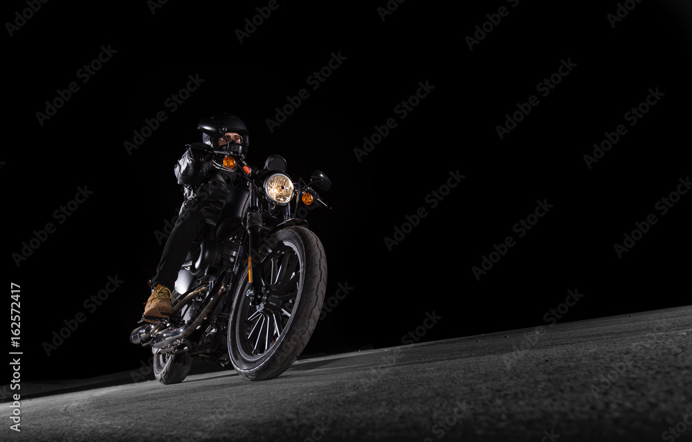 Fototapeta premium Rowerzysta jeździ motocyklem po drodze nocą. Sezon motocyklowy zaczyna się teraz wiosną.