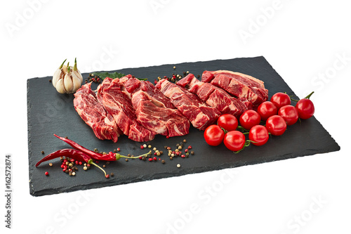 Photography Fresh raw beef steaks with pepper and tomatoes on black slate board