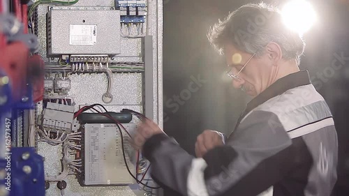Close-up of experienced man working with electric meter.