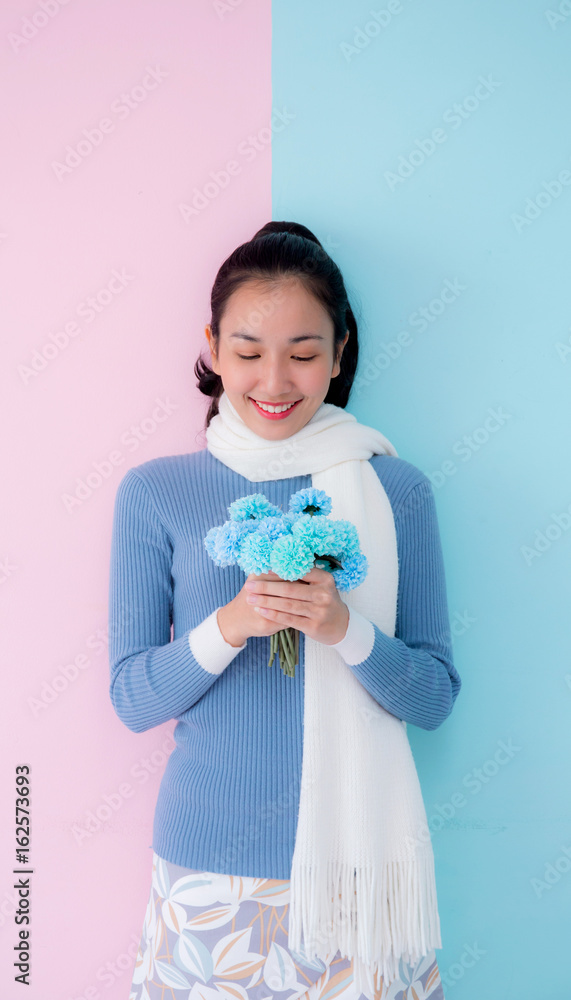 Happy beautiful young woman asian holding flower on living room pastel color tone. Happy beautiful young woman asian holding flower on living room pastel color tone.