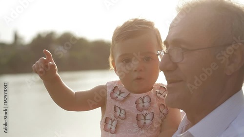 Grandfather with his granddaughter taking a walk by the lake