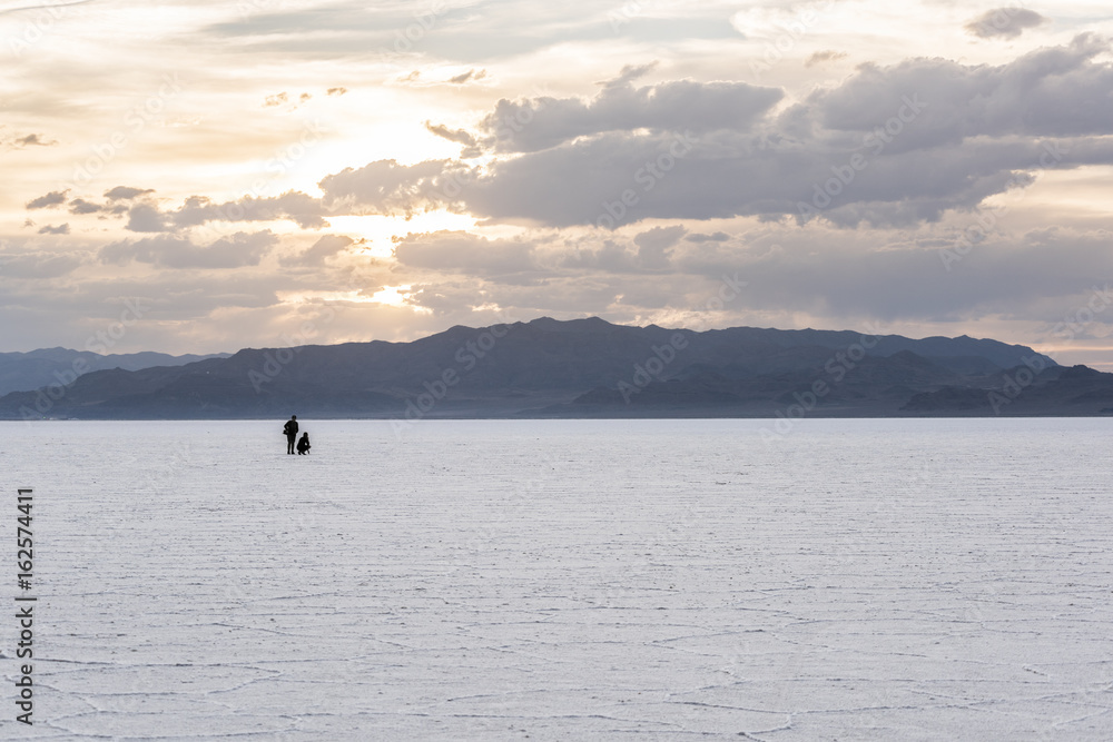 Fototapeta premium Two people in the distance in the vast salt flats near Salt Lake City, Utah during sunset