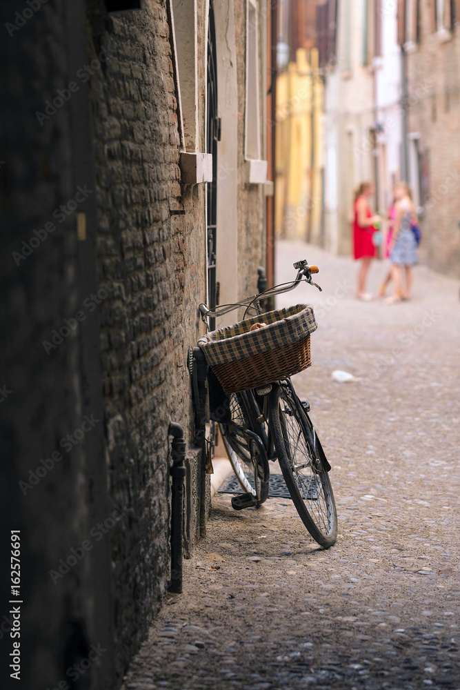 Bicycle parked near the wall of an ancient house in an Old Town of Ferrara, Italy