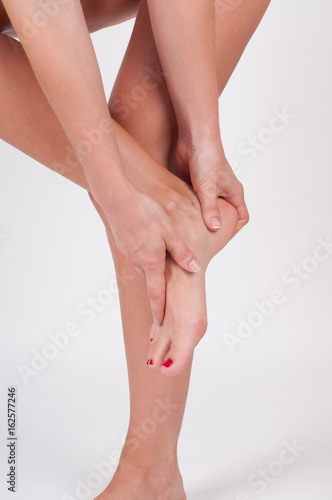 Fototapeta Naklejka Na Ścianę i Meble -  Ankle pain. Female legs. Woman massaging her ankle