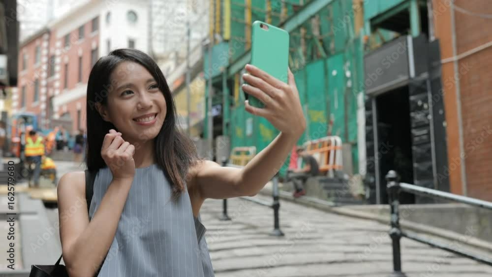 Woman taking photo with cellphone in Pottinger Street Woman taking photo with cellphone in Pottinger Street