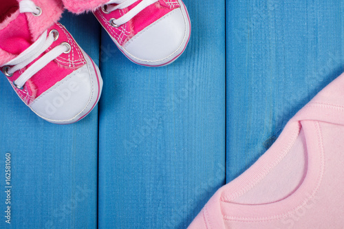 Shoes and bodysuits for baby, concept of expecting for newborn, copy space for text on boards