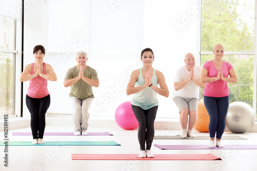 Group of people practicing yoga in gym