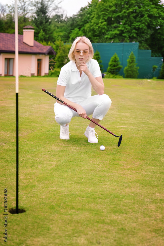 Fototapeta premium Beautiful young woman playing golf on course in summer day