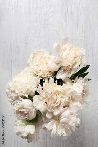 Top view of beautiful peonies on wooden table