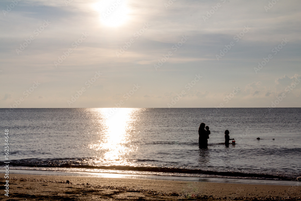 Father, mother, and child Enjoy the sea at dawn.