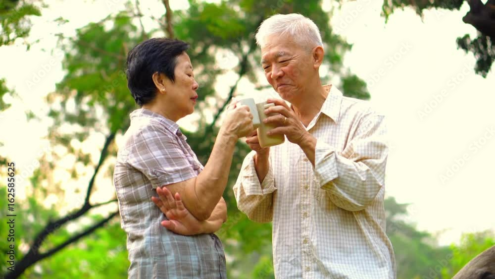 Asian senior couple showing affectionate and care through a cup of coffee in morning bright natural park Asian senior couple showing affectionate and care through a cup of coffee in morning bright natural park
