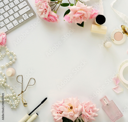 Beauty blog concept. Female make up accessories and bouquet of pink roses on white background. Flat lay, top view feminine desk, workspace with laptop. Copy space.