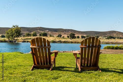 Two Adirondack chairs before a lake in a mountainous valley in San Diego, California. 