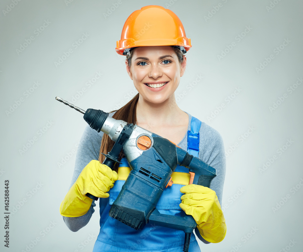 Smiling woman wearing helmet holding drill tool. Smiling woman wearing helmet holding drill tool.