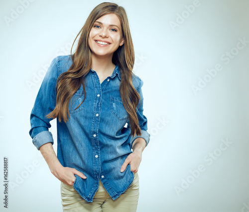 Smiling girl standing against gray background.