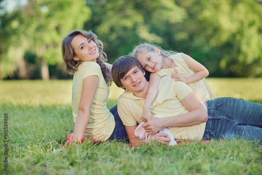 Happy family lying on grass in park.