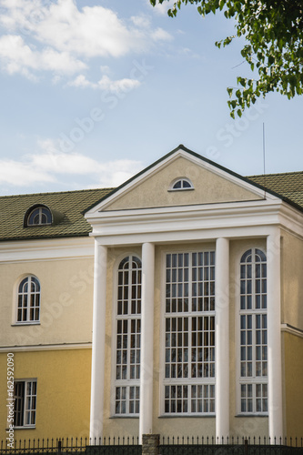 Close-up front wall of cottage house with gables and arched windows in sunlight. © Олександр Болюх