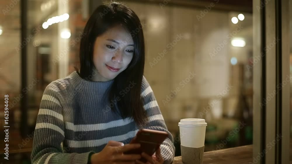 Woman using cellphone in cafe at night Woman using cellphone in cafe at night