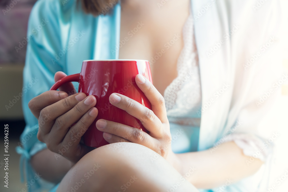 Woman sitting at opened window drinking coffee and looking outside enjoys of rest Woman sitting at opened window drinking coffee and looking outside enjoys of rest