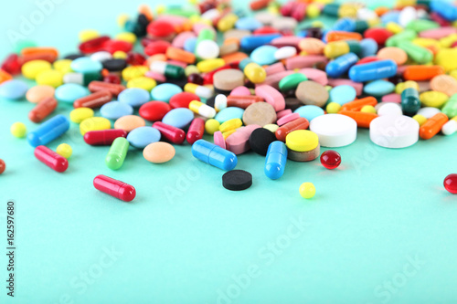Different colorful pills on mint background