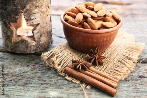 Almonds in bowl with cinnamon and star anise on wooden table