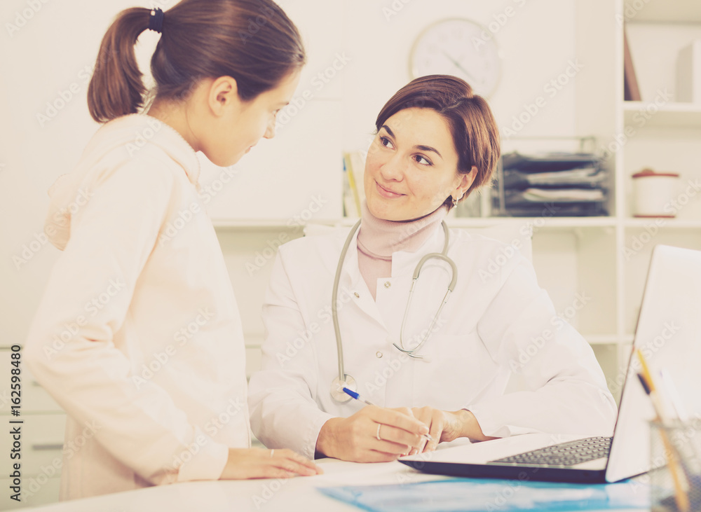 Fototapeta premium Doctor fills patient card for girl