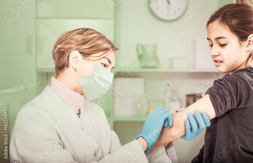 Nurse in mask making injection