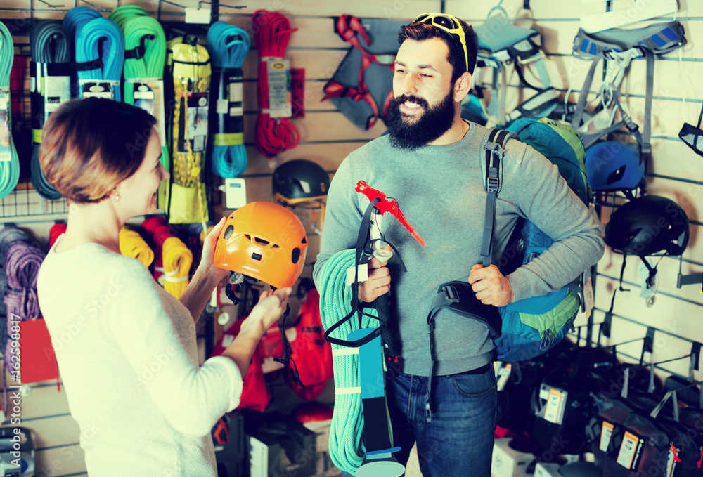 Smiling male and woman buying alpinism equipment