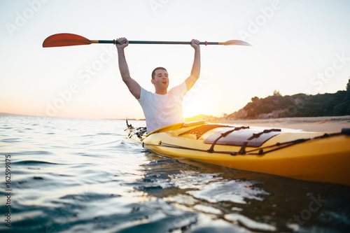 Happy man holding kayak oars high
