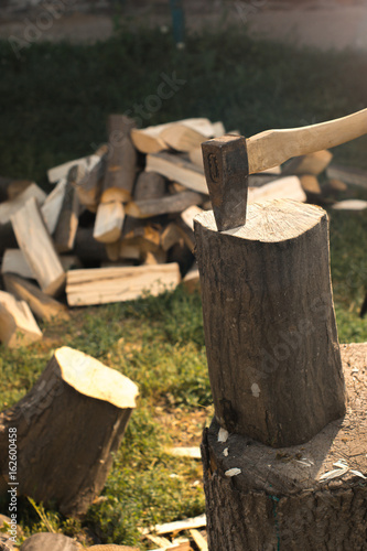 The ax in a log against the background of firewood.