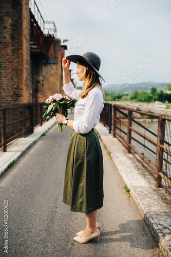 Beautiful woman holding a bunch of peony flowers