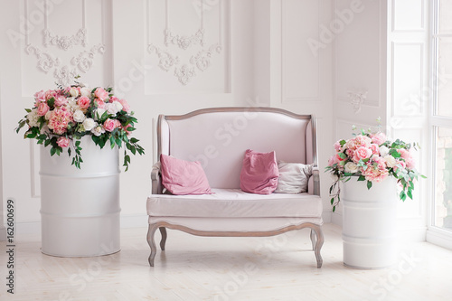фотографія Interior of a snow-white living room with a vintage sofa and flowers