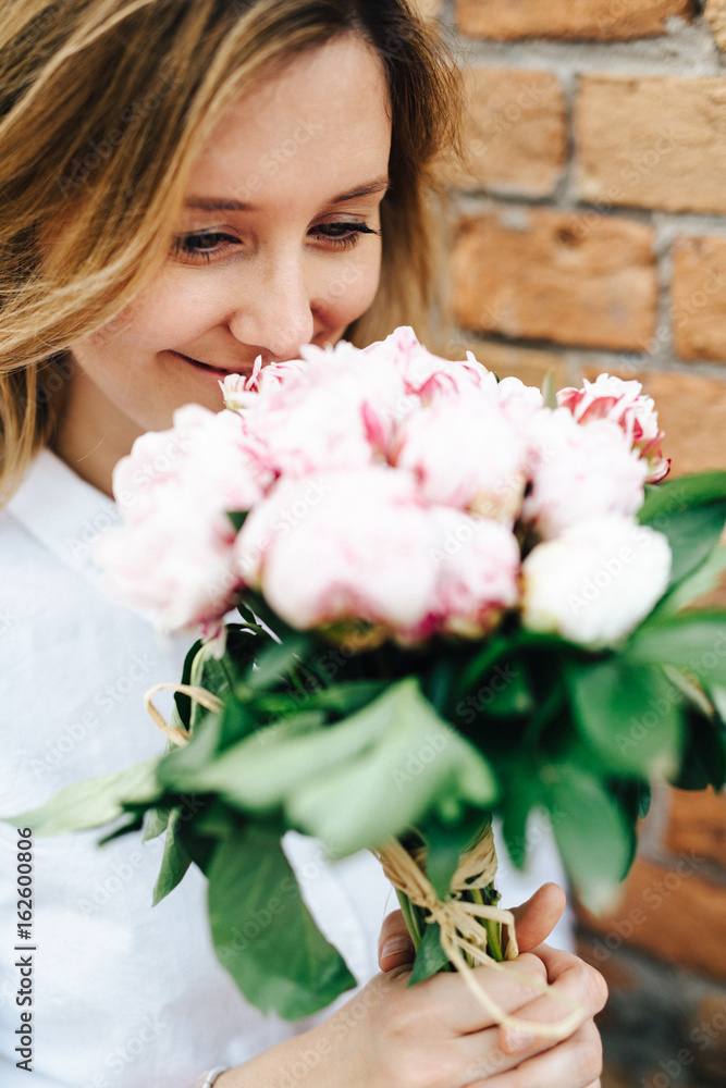 Beautiful woman holding a bunch of peony flowers Beautiful woman holding a bunch of peony flowers