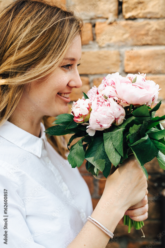 Beautiful woman holding a bunch of peony flowers Beautiful woman holding a bunch of peony flowers