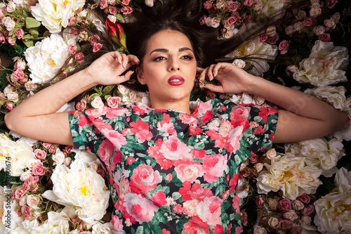 Sensual woman lying on flowers in studio photo. Beauty and fashion. Cosmetics and skincare