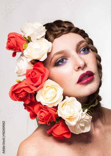 Woman wearing flowers on her head in creative portrait in studio photo. Beauty and fashion. Glamour and summer